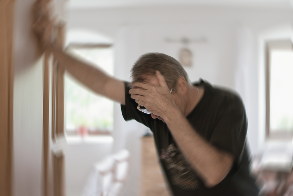 Woman experiencing sinus infection symptoms in NYC Man braces himself against a wall while experiencing vertigo.